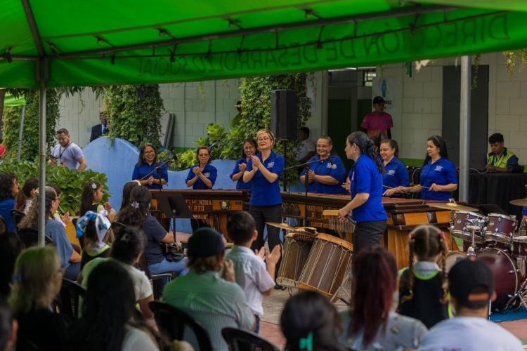 Integrantes de la Marimba Femenina de Concierto ejecutando el instrumento nacional frente a cientos de niños durante una jornada educativa.