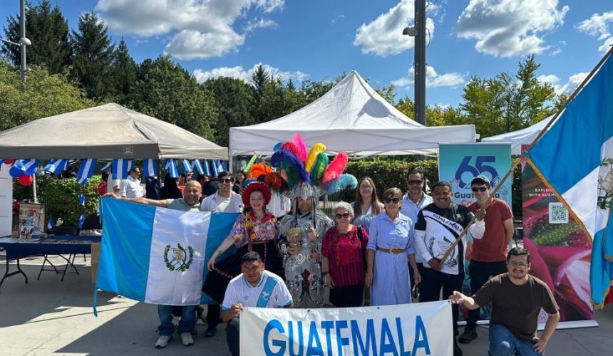 Stand promocional de Guatemala en el Festival Latino de Ottawa con artesanías, imágenes de destinos turísticos y muestra cultural.