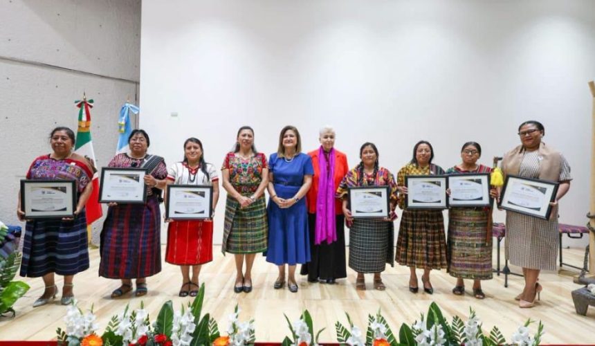 Siete mujeres indígenas distinguidas con la Orden Ütz Samaj sosteniendo sus diplomas y condecoraciones durante la ceremonia oficial.